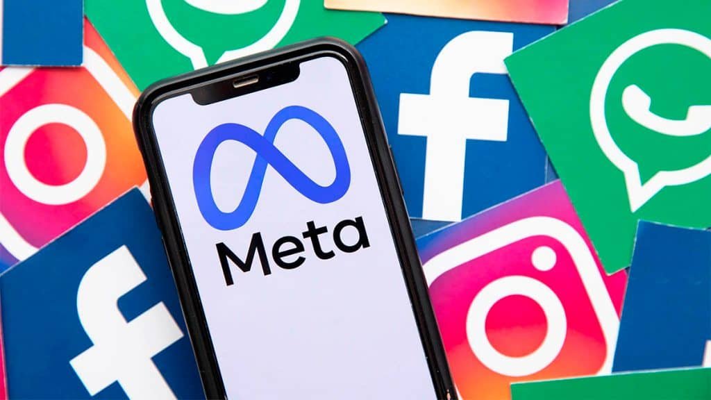 Celular com logomarca da Meta e ícones do Instagram, Facebook e WhatsApp ao fundo